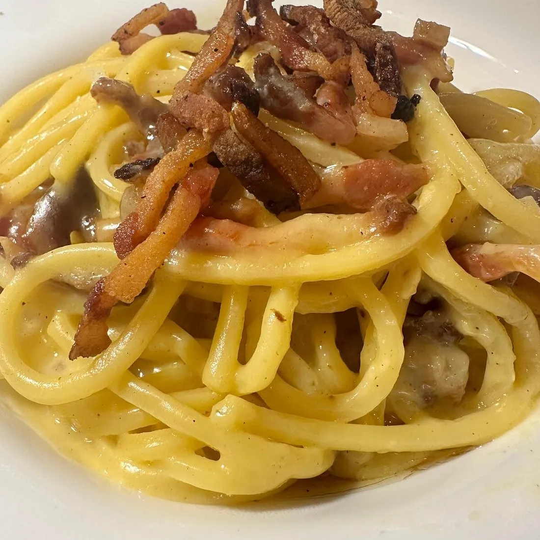 Piatto di spaghettoni alla carbonara con guanciale croccante e pepe