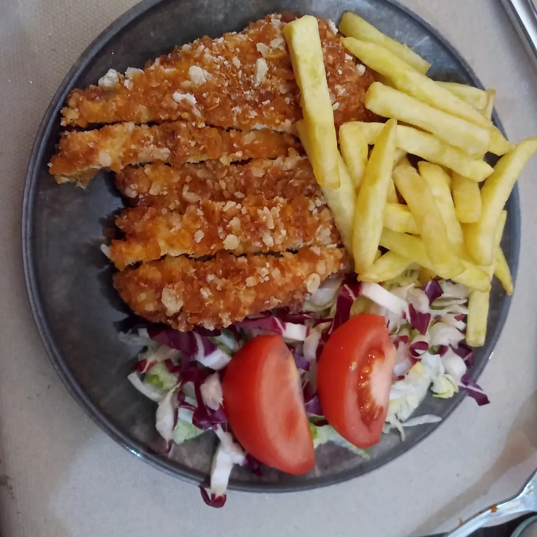 Pollo impanato a strisce con patatine fritte, insalata e pomodoro